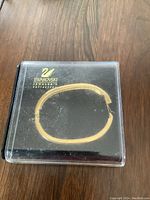 Closed Swarovski bracelet inside clear plastic display case with Swarovski swan gold logo on lid