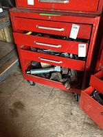 Front view of the tool chest with drawers partially open showing tools inside such as gloves and metal tools.