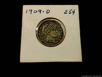 Obverse side of the 1909-D Barber Quarter showing Liberty head and date 1909 within a cardboard holder labeled with year and denomination.