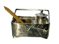 Front angle of silver basket with floral engraving, salt well with wooden spoon, and small pepper shaker on top surface.