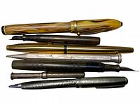Photo of a group of 7 vintage pens and pencils laid out showing various styles and materials.