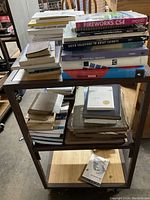 Top view of two shelves filled with stacks of vintage and newer books, some with worn covers and varied thicknesses, showing an assortment of titles related to design and miscellaneous topics.