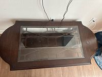 Top down view of rectangular wood coffee table with glass inset top showing frame details and some wear.