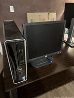 Dell desktop computer tower and Dell monitor on a wooden desk.