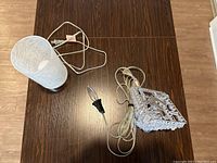 Photo of touch lamp with frosted glass shade and metal base alongside crystal chandelier with cord and bulb on wooden table.