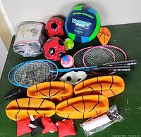 Photo showing all miscellaneous outdoor game items included in the lot spread out on a green surface.