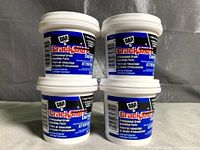 Photo of four DAP Crackshot spackling paste containers stacked in two rows of two, showing labels and lids.