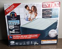 Box packaging of the Intex Dura-Beam Deluxe queen airbed showing product images, descriptions, and key features including 24 inch height, pillow top, and Dura-Beam technology.
