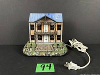 Front perspective of stained glass house lamp showing the textured base and wired plug.