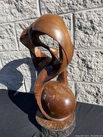 Full view of the wood sculpture showing side and top curves, highlighting the birds and wooden base.