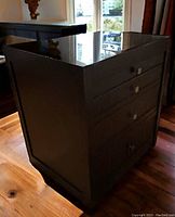 Side view of the extendable dark wood desk showing four drawers with square handles and glossy glass top