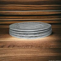 Stack of five white ceramic dinner plates with gray dotted border pattern on wooden surface