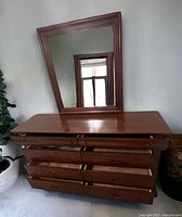 8 drawer cherry dresser with some drawers open and mirror leaning on top