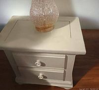 Close-up photo of the nightstand showing the two drawers and surface scratches.