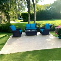 Full set view on patio showing loveseat, two armchairs and coffee table on outdoor rug under tree shade.