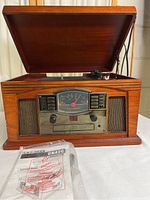 Front view of the Crosley CR42C unit with lid open showing the turntable, front control panel with radio dial, cassette tape slot, and stereo speakers.