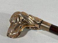 Close-up of champagne colored metal dog head handle showing detailed sculptural features.