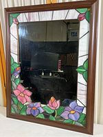 Full view of rectangular wall mirror with stained glass floral border and solid wood frame.
