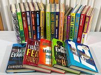 Full set of 22 hardcover Janet Evanovich books, showing spines with Stephenie Plum series titles and others, all dust jackets present