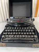 Front view of Remington Noiseless Portable typewriter showing round glass-topped keys and black body.