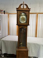 Full front view of tall Ridgeway grandfather clock showing wooden case, glass front panels, and clock face.