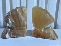 Pair of vintage onyx marble bookends shaped like scallop shells, side-by-side showing both fronts.