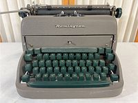 Front view showing gray body, green keys, and Remington logo on front panel of typewriter.