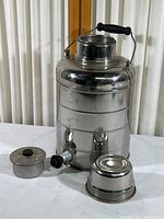 Full view of large Stanley stainless steel thermal jug with handle, spigot, and lid cup on side