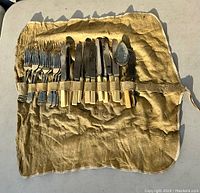 Full set of antique silver plated flatware within original tan chamois storage bag, laid out showing forks, knives, and spoon.