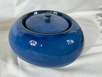 Overall view of blue ceramic fire pot with lid showing glossy finish and rounded shape.