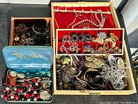 Photo of multiple boxes and trays filled with assorted jewelry pieces of various styles and materials.