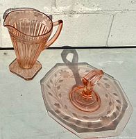 Pitcher and dessert serving tray in pink Depression glass displayed together showing overall shapes and details.