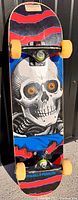 Full view of the Powell Peralta skateboard showing the 'Ripper' skull graphic, yellow wheels, and black trucks.