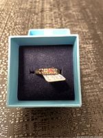 Front top view of 10K gold ring with multi-colored stones in blue box