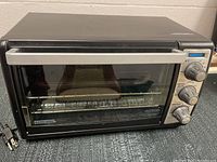 Front and side view of Black and Decker convection toaster oven showing handle, glass door, and three control knobs.