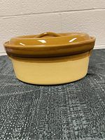Side view of the lidded crockery casserole showing the two-tone color and base shape.