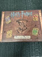 Closed game box for Harry Potter Hogwarts Battle with house crests and title visible.