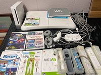 Complete lot arranged on table showing console, balance board, game cases, controllers, and manuals.