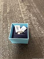 Ring displayed in blue jewelry box with tag indicating size 7 and 925 silver.