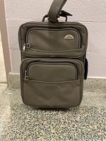Front view of Samsonite carry-on suitcase showing front zippered compartments, fabric texture and badge.