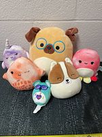 Full lot of 5 assorted Squishmallow characters including a pug, corgi, octopus, narwhal, and small blue-green figure with sunglasses