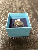 Photo of sterling silver ring with triple band design and clear stones inside a blue box