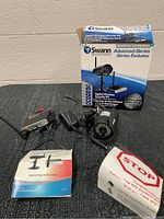 Full kit including Swann Advanced-Series security camera, receiver, power adapters, mounting bracket, and manual with the original product box.