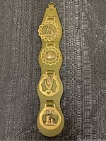 Full view of olive green leather horse strap with four brass medallions showing different decorative elements.