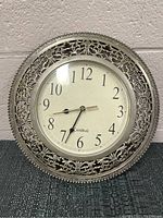 Front view of the vintage Cardinal wall clock showing white face, black numerals, and silver ornate metal frame.