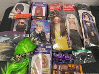 Photo showing the variety of wigs including packaged and loose neon green hairpieces along with costume accessories like fake beard, novelty glasses, and black mesh fabric.