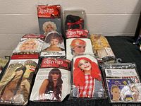 Full view of all wigs in their packages and two packs of wig caps arranged on table.