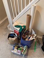 Full lot showing various bags, ribbons, and rolls of wrapping paper grouped together on floor by staircase.