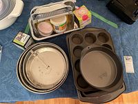 Various baking pans including round, rectangular and springform pans and muffin tins on a table.