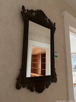 Full view of the rectangular wall mirror with ornate carved wood frame, showing its overall size and profile on a wall.